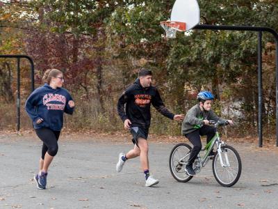 student rides bike with instructors